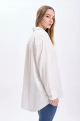 Camisa blanca de lino de manga larga con cuello clásico, cierre frontal con botones y bolsillo en el pecho.