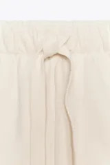 Shorts color crudo de tiro medio con cintura elástica ajustable con cordones y bajo desflecado.