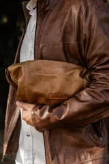 Necessaire de cuero natural color marrón, confeccionado de forma artesanal con un diseño funcional y atemporal. Cuenta con laterales ajustables para adaptar su capacidad, interior forrado y reforzado, y cierre superior metálico. Marca Soriame.
