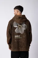 Buzo canguro negro con capucha, de corte oversize y estética lavada. Presenta un bolsillo tipo canguro y puños con orificio para el pulgar. Estampado con texto en el lateral izquierdo.