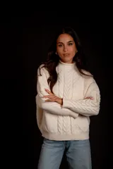 Sweater color crudo con cuello alto y diseño trenzado.