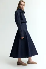 Pollera midi de denim azul oscuro, corte evasé y costuras verticales decorativas.