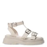 Sandalias bajas color beige con plataforma y tiras anchas con hebillas plateadas, estilo romano.
