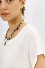 Remera blanca de lino con calce al cuerpo y mangas cortas. Presenta bordados de lentejuelas y mostacillas en los hombros.