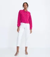 Campera color fucsia de crepe con cuello de camisa, manga abullonada, cierre frontal con botones y bolsillos frontales aplicados.