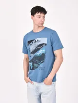 Remera azul con estampado de paisaje en tonos grises y negros.