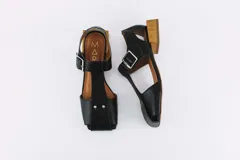Sandalias de cuero negro con punta cuadrada, tira central con hebilla y taco cuadrado de madera.