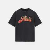 Camiseta de corte regular, color negro con efecto gastado (acid wash), con estampado frontal en tipografía cursiva de color rojo y amarillo con efecto degradado.