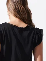 Remera negra de modal con escote en V y aplique de puntilla en mangas y escote. Detalle fruncido en hombros.