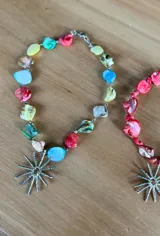 Collar corto con cuentas de colores y dije plateado en forma de sol.