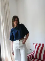 Top color beige de tejido de punto, con mangas cortas y cuello redondo. Presenta un bordado del escudo en la parte delantera.