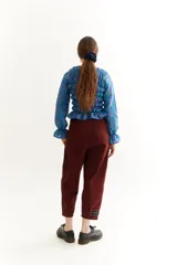 Blusa de lino a cuadros en tonos rosa, violeta y marrón, con cuello alto fruncido, mangas largas con volantes y corte crop.