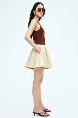 Pollera mini circular color beige, con bolsillos laterales discretos y cierre oculto con corchete atrás.