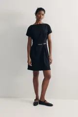 Vestido negro a la rodilla con escote bote y pliegues de caja invertidos adelante y atrás. Modelo de manga corta con cintura entallada, cinturón extraíble con hebilla de metal y bajo recto. Cierre oculto en la espalda. Sin forrar.