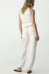 Pantalón jogger color gris claro, de tiro alto con cintura elástica ajustable con cordones, bolsillos delanteros y traseros con solapa, y puños elásticos en los tobillos.