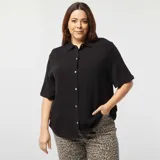 Camisa negra de lino con botones blancos, mangas cortas con dobladillo y cuello clásico.