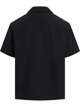 Camisa negra de manga corta con cuello cubano y bolsillo de parche en el pecho. Cierre frontal con botones y logo de la marca en el bolsillo.