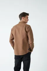 Camisa marrón de manga larga con bolsillo en el pecho y cierre con botones.