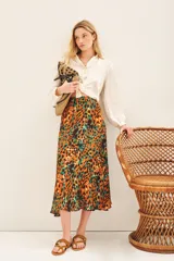 Falda midi de satén estampado con diseño animal print en tonos naranja, verde y negro. Tiene corte amplio y elástico en la parte trasera de la cintura.