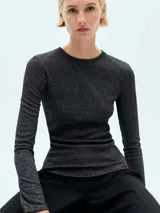 Remera negra con brillo, de tejido de punto fino y manga larga.