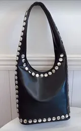 Cartera tipo hobo de cuero sintético color negro, con tachas plateadas en los bordes.