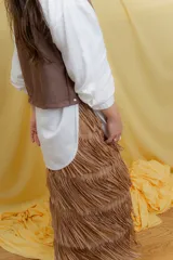 Pollera midi color marrón con flecos en capas y cierre trasero con cremallera.