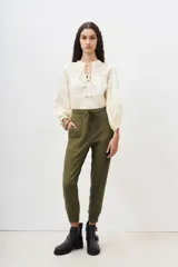 Pantalón tipo babucha color verde militar, confeccionado en gabardina elastizada, con ajuste en tobillos y cintura regulable con cordón a tono. Cuenta con bolsillos diagonales en el frente y bolsillos con solapa y botón en la parte trasera.