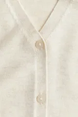 Chaleco de punto fino color crema con escote en V y botonadura frontal.