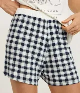 Conjunto de pijama de dos piezas compuesto por una remera de manga corta color blanco tiza con estampa de frutas en negro y un short estampado a cuadros en tonos azules y blancos.