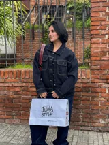 Campera de jean azul oscuro con costuras en hilo ocre, corte recto, cuello clásico, bolsillos frontales con solapa y cierre con botones metálicos.