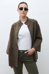 Chaqueta tejida de punto color verde oliva, con cuello alto y cierre frontal de botones a presión. Presenta bolsillos delanteros aplicados y mangas amplias de largo tres cuartos.