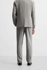 Pantalón de vestir gris claro con textura, corte regular fit, bolsillos laterales y traseros de doble vivo con botón. Cierre frontal con cremallera y botón.