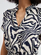 Vestido corto con estampado floral en tonos azul y blanco, con cuello en V, mangas cortas y lazo en la cintura.