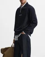 Buzo negro de cuello alto con cierre metálico y logo bordado en el pecho.