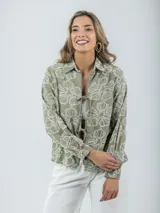 Blusa color crudo con bordados florales, cuello camisero y mangas largas.