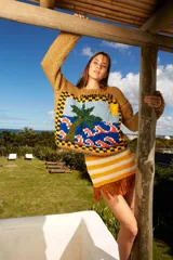 Minifalda tejida a mano en hilado de algodón, con diseño a rayas horizontales en color amarillo y blanco. Presenta flecos marrones en el ruedo.