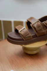 Sandalias de cuero color marrón con plataforma forrada en cuero y hebillas doradas.