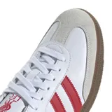 Zapatillas Adidas Samba blancas con tres tiras rojas a los costados, detalle rojo en el talón y suela de goma marrón.