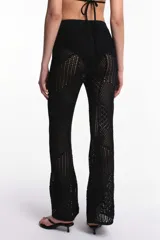Pantalón negro de tejido crochet calado con diseño patchwork y corte acampanado.