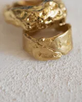 Anillo plateado con textura irregular y diseño rústico.