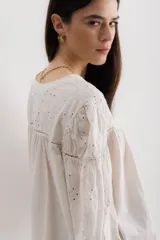 Camisa celeste de algodón con bordado calado, cuello en V y mangas largas abullonadas con puños elásticos.
