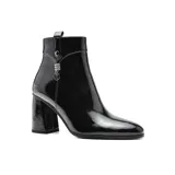 Bota corta de charol negro con punta fina, cierre lateral y detalle de colgante metálico.