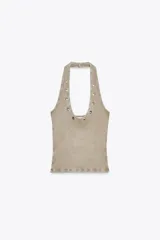Camiseta blanca de rib con efecto lavado, cuello halter y escote redondo. Detalle de arandelas metálicas en el escote.
