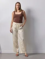 Pantalón palazzo color crema, marca Nanette, con pretina elastizada, lazo de ajuste y bolsillos delanteros.