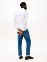 Camisa blanca de popelina con tecnología flex, corte slim, cuello con botones, cierre con botones, manga larga y logo de Tommy Hilfiger bordado en el pecho.