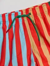 Short de baño a rayas verticales rojas, celestes y beige con cordón de ajuste verde.