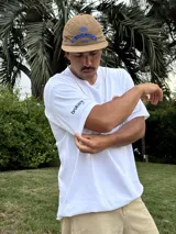 Remera blanca de algodón con estampado de un balón de fútbol americano y la frase "Together, we are America" en rojo. Incluye una firma en negro debajo del estampado.