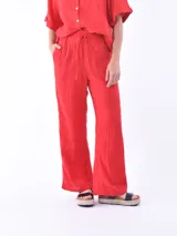 Pantalón de lino color rojo, de corte amplio y cintura elastizada con cordón ajustable.