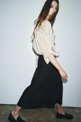 Falda larga negra de tiro medio confeccionada en hilatura con mezcla de algodón. Detalle de bordados florales a tono. Bajo evasé y cierre con cremallera oculta en costura.