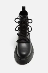 Bota de cuero negra con cordones, cordonera con nueve pasados, tirador trasero y suela track con volumen.